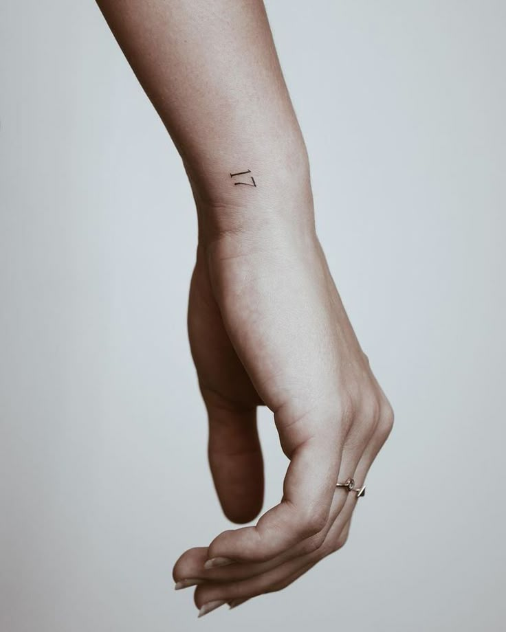 a woman's hand with a small tattoo on the left side of her arm