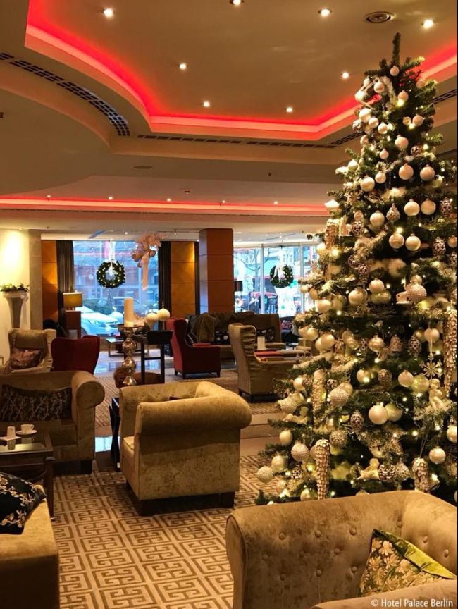 a decorated christmas tree in the middle of a living room with couches and chairs