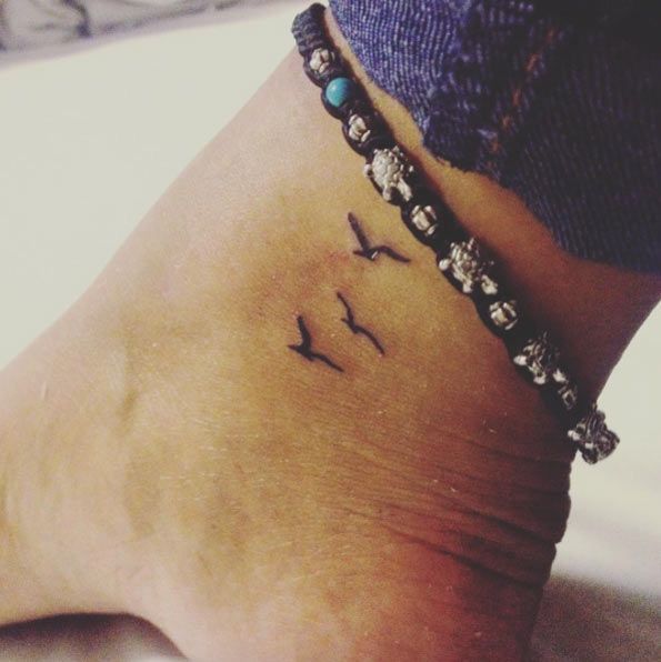 a woman's foot with a small bird tattoo on the side of her ankle