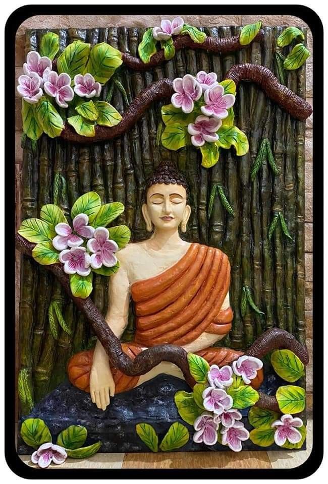 a buddha statue sitting on top of a wooden table next to flowers and bamboo sticks