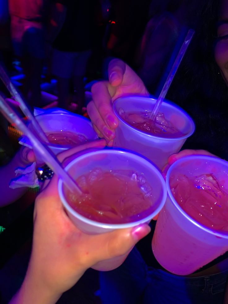 three people holding cups with drinks in them