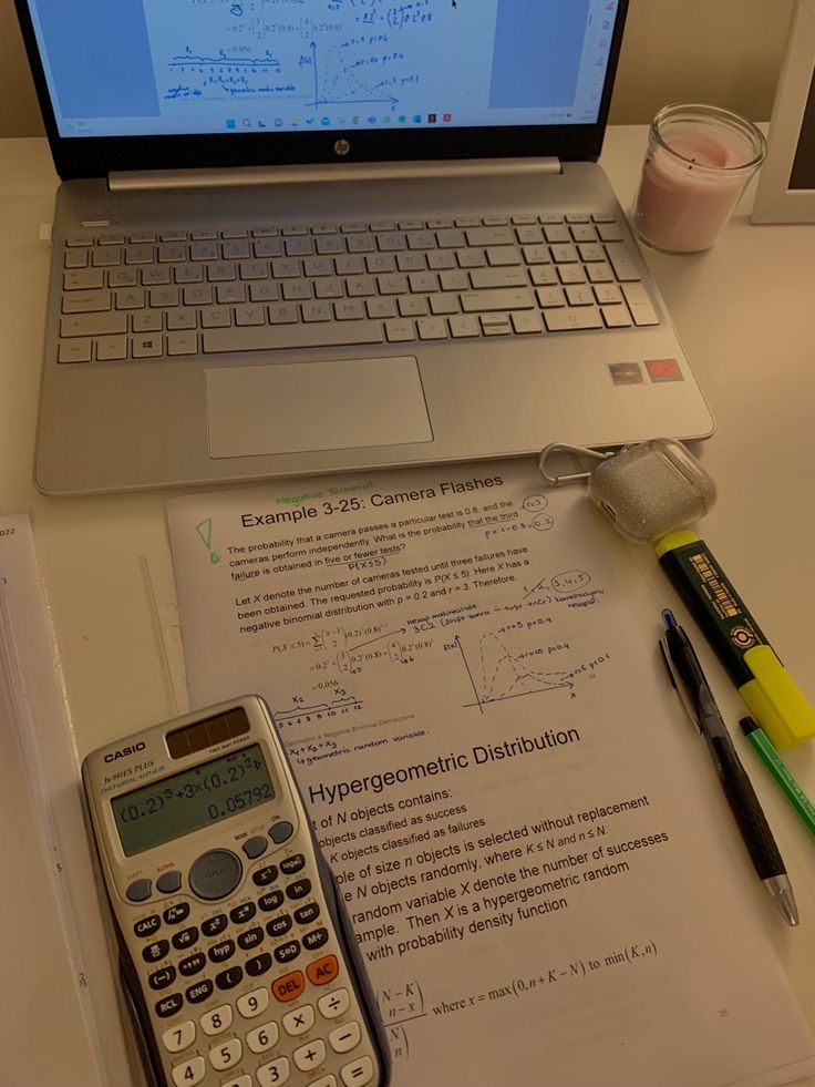 an open laptop computer sitting on top of a desk next to a calculator