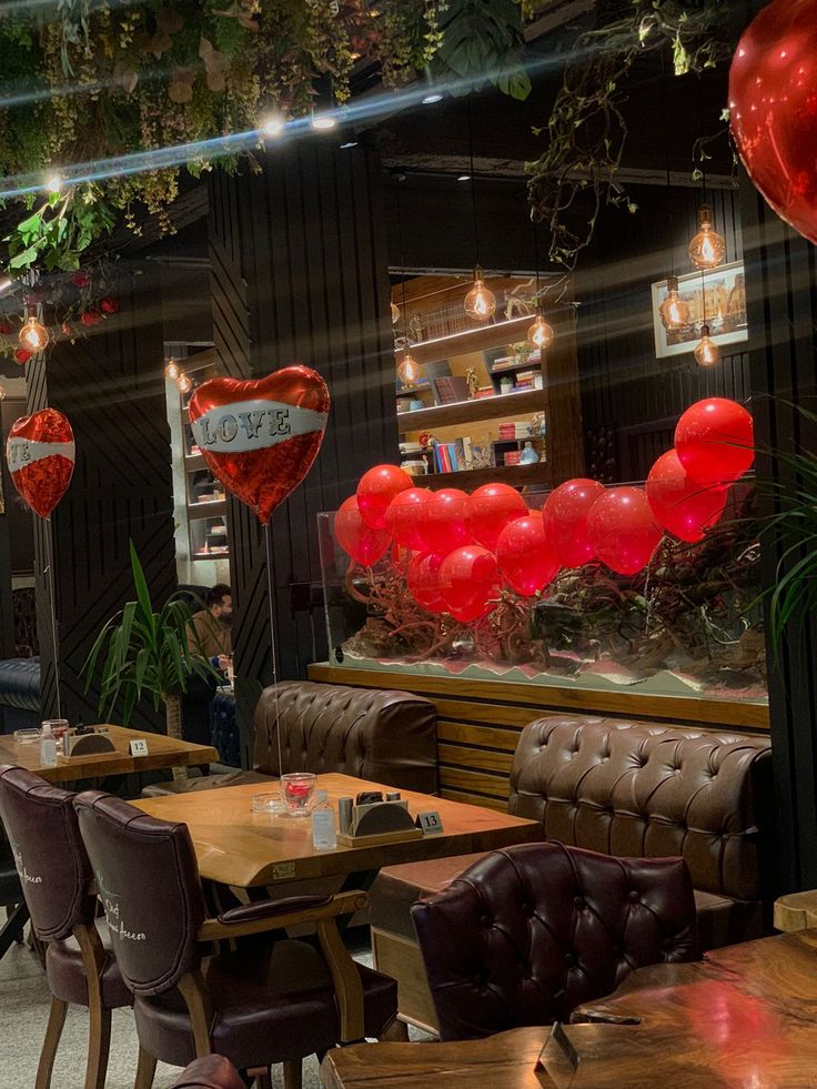 a restaurant with tables, chairs and balloons hanging from the ceiling in the shape of hearts