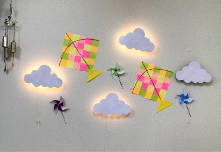 several colorful kites are hanging on the wall next to each other with lights around them