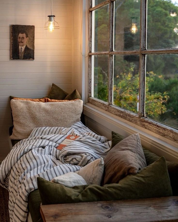 a bed sitting under a window next to a wooden bench