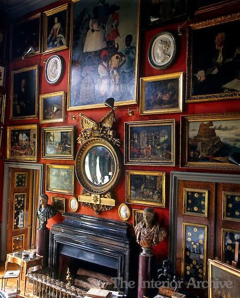 a room filled with lots of paintings and pictures on the wall next to a fire place