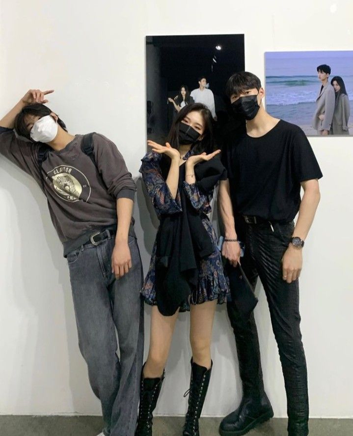 three people standing next to each other wearing masks