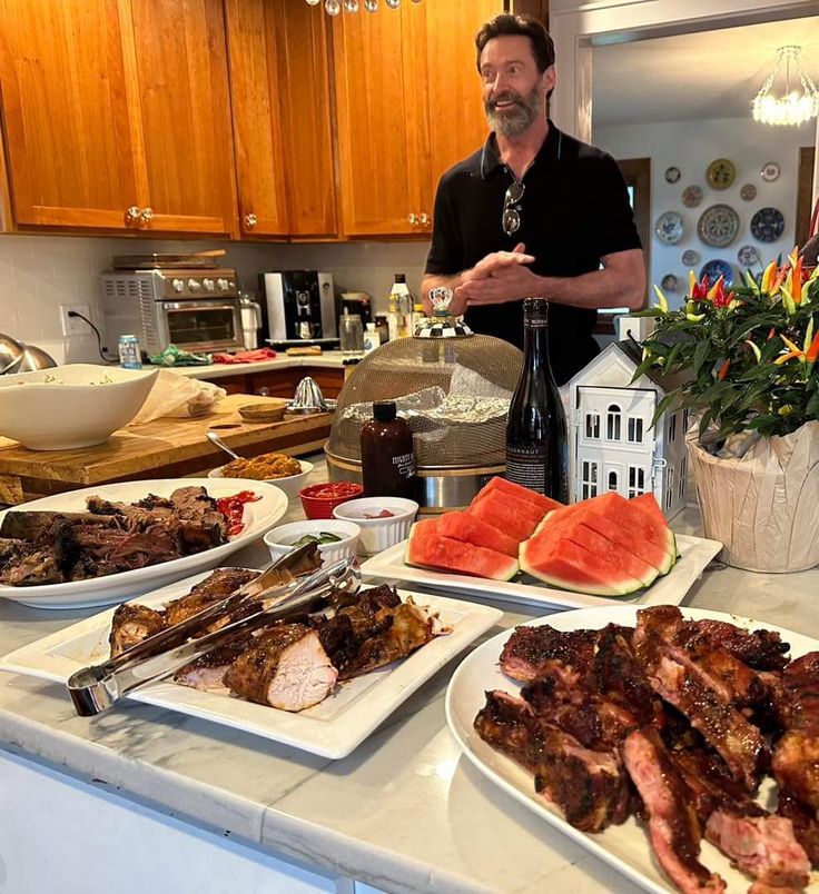 a man standing in front of a kitchen counter filled with plates of food and watermelon slices