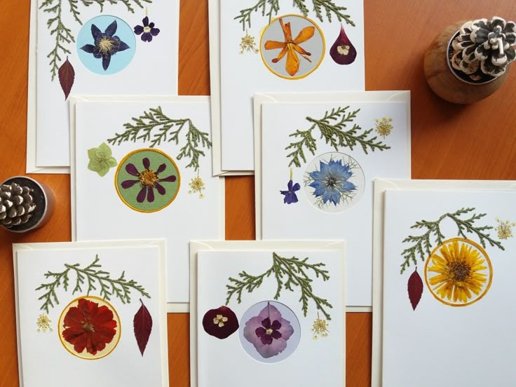 six cards with different designs on them sitting on a table next to a pine cone