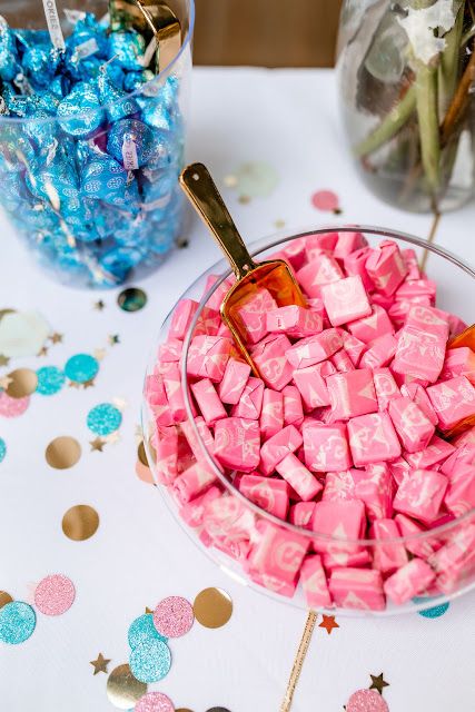 pink and blue candies in a glass bowl on a table with confetti