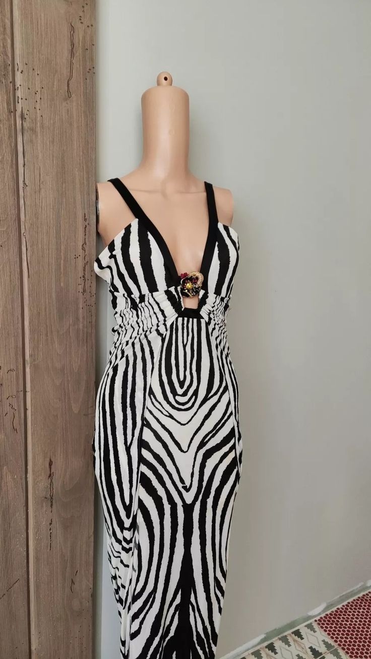 a mannequin wearing a zebra print dress next to a wooden wall with a black and white pattern on it