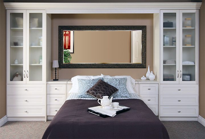 a bedroom with a bed, dresser and mirror on it's wall above the headboard