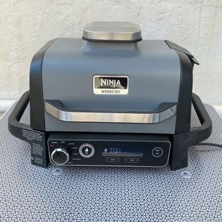 a black and silver grill sitting on top of a table next to a white wall