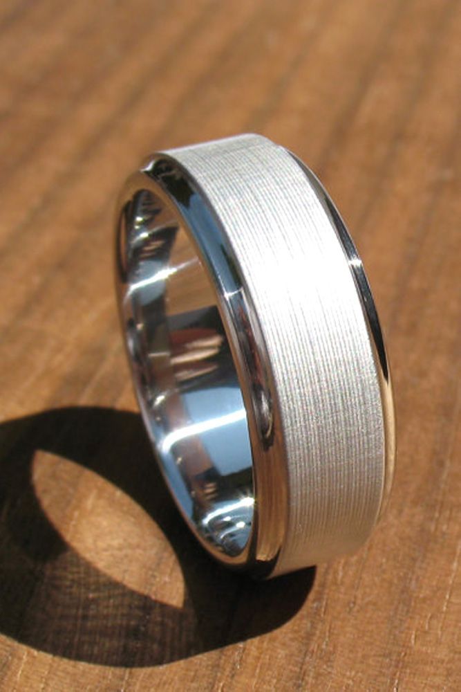 a silver ring with a white interior on a wooden surface in front of a shadow