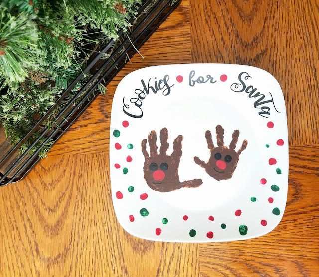 a plate with two handprints on it sitting next to a potted plant