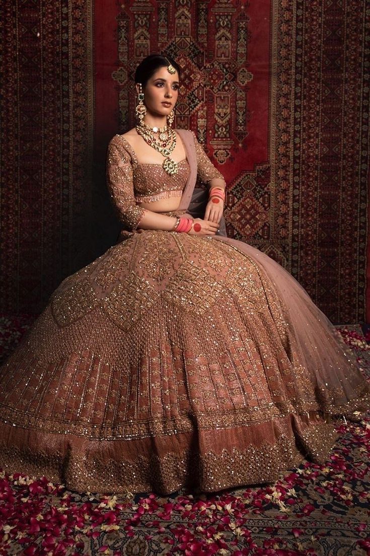 a woman in a brown dress sitting on a red carpet with an ornate rug behind her