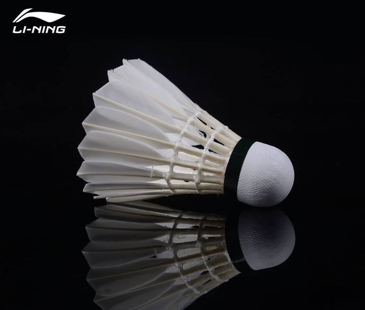 a close up of a white badminton ball on a black surface with the reflection of it