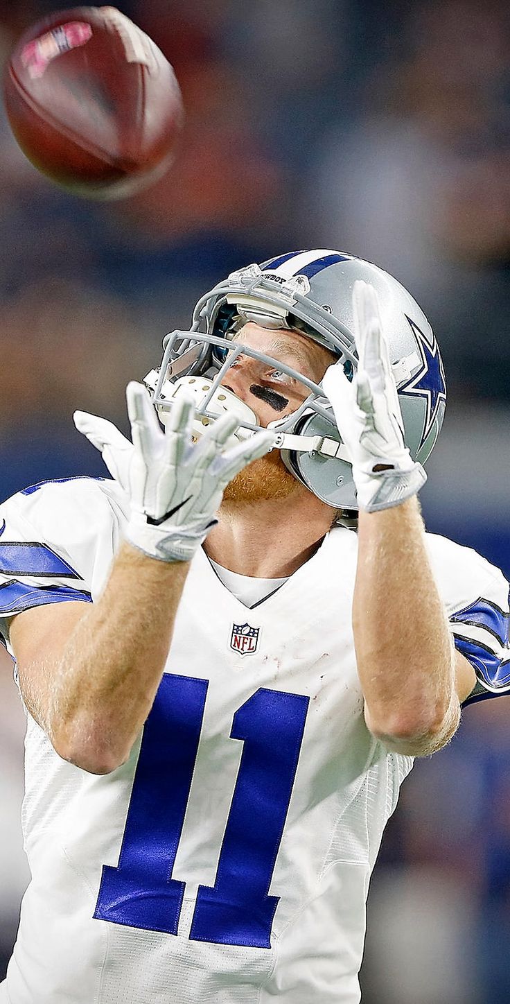 a football player throwing a ball in the air with one hand and another holding his head