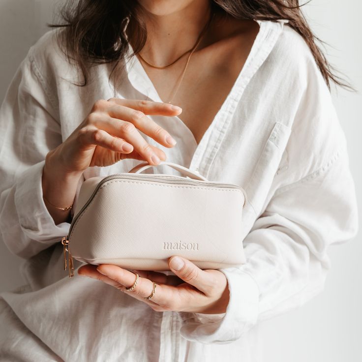 a woman holding a white purse in her hands