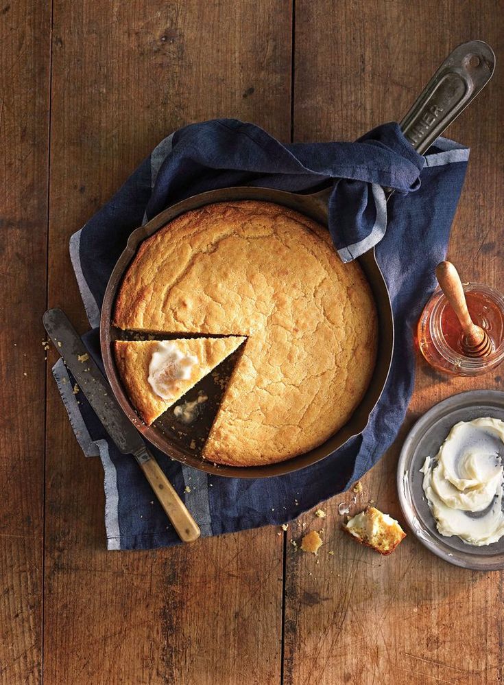 a pie sitting on top of a wooden table next to a knife and some butter