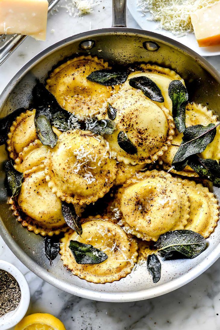 a pan filled with ravioli and spinach on top of a marble countertop