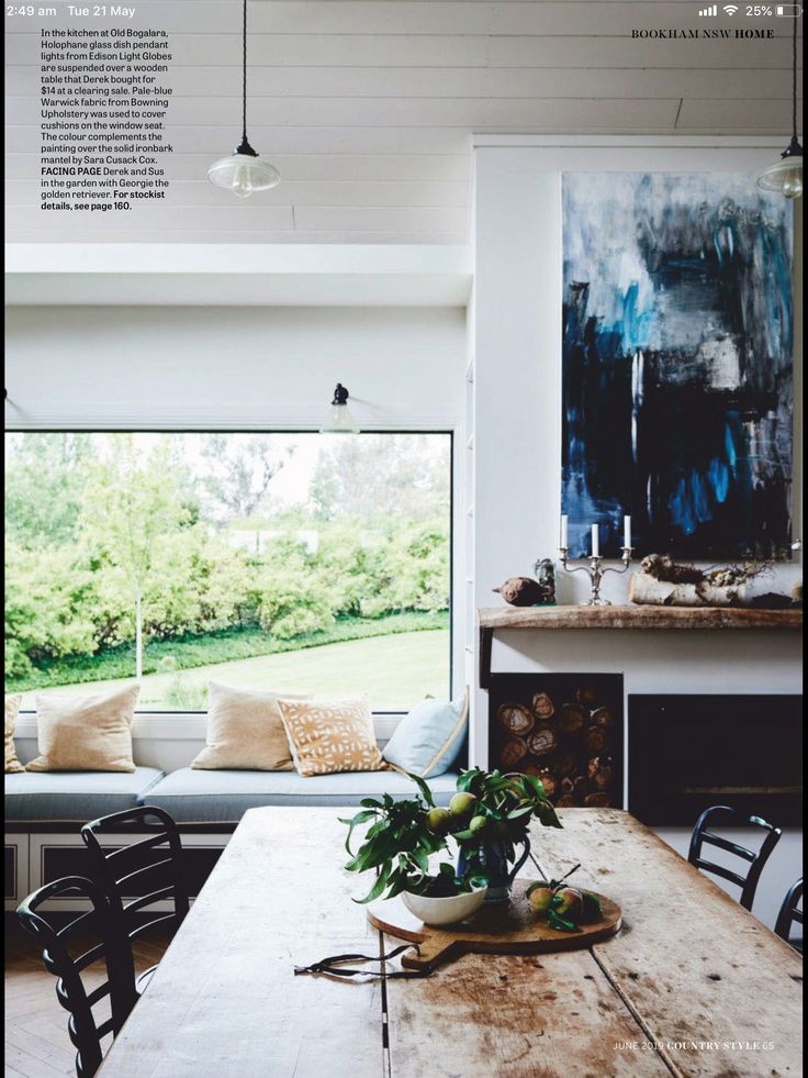 a wooden table sitting in the middle of a living room next to a large window