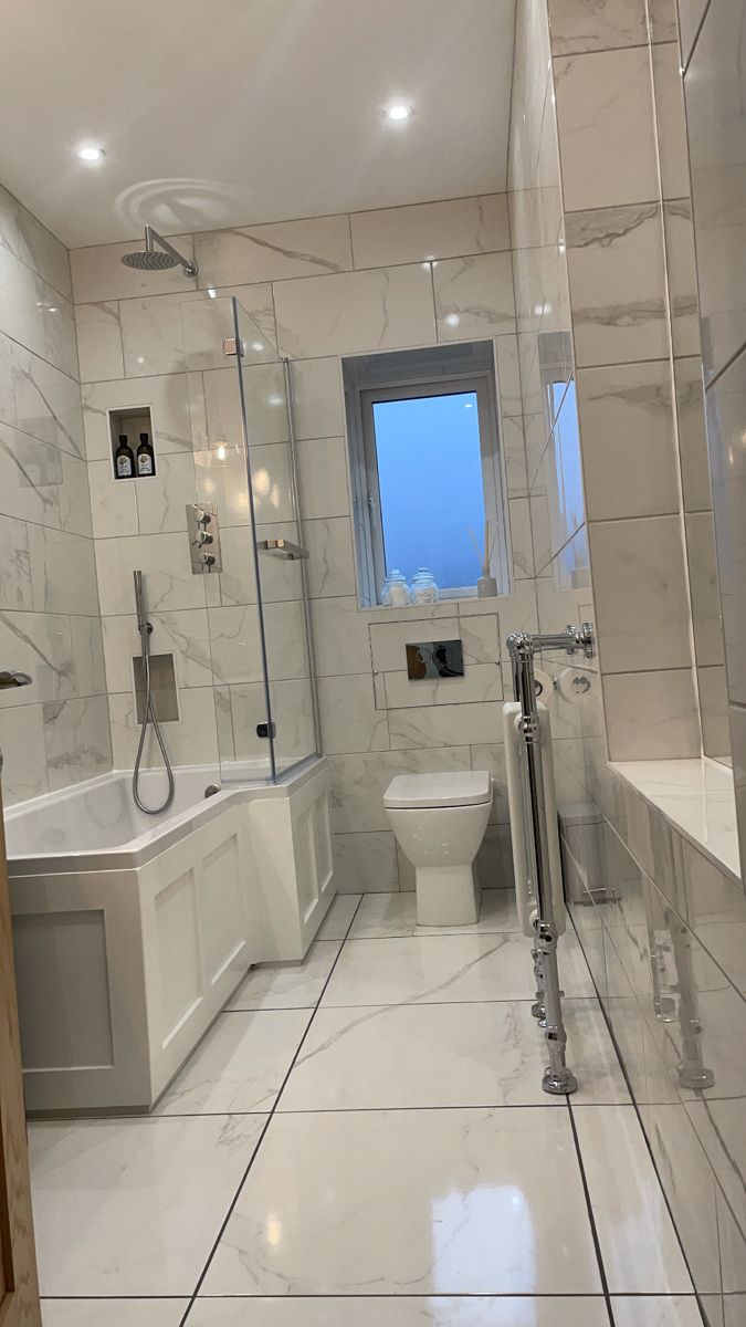 a large bathroom with white marble floors and walls, along with a walk in shower