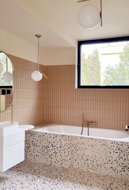 a bath tub sitting under a large window next to a white sink and counter top