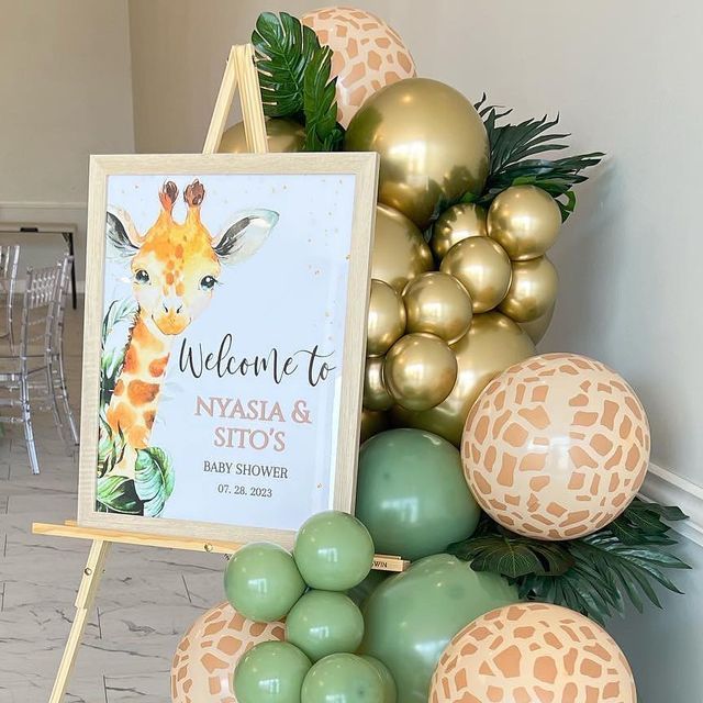 a welcome sign and balloons are on display at a baby's first birthday party