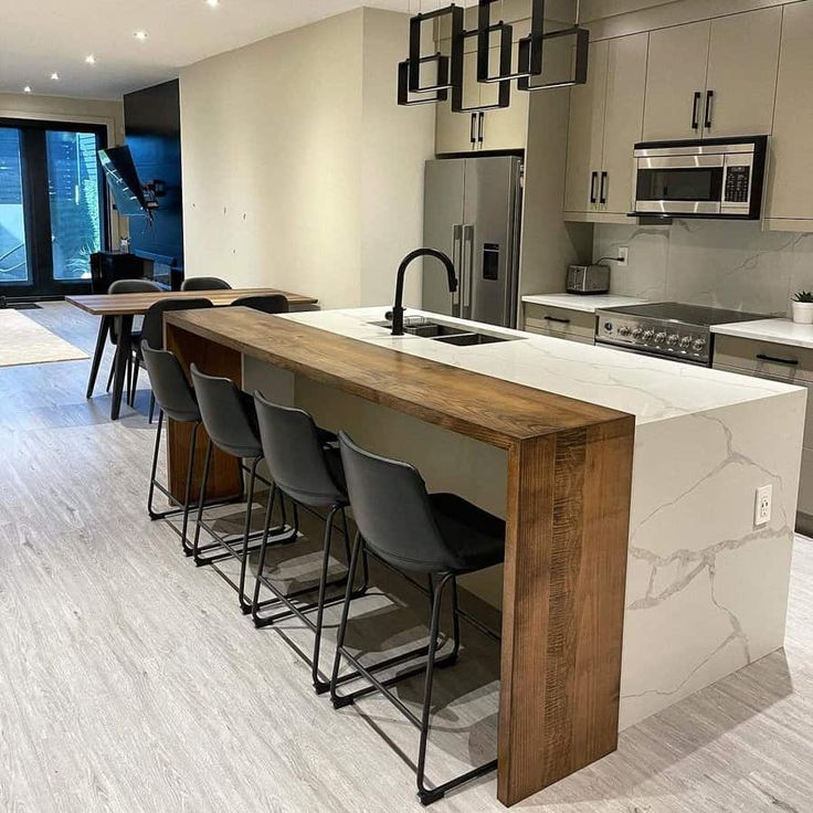 a modern kitchen with marble counter tops and bar stools next to the stove top