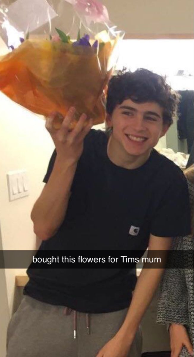 a young man holding flowers in front of his face with the caption, bought this flowers for tims mum