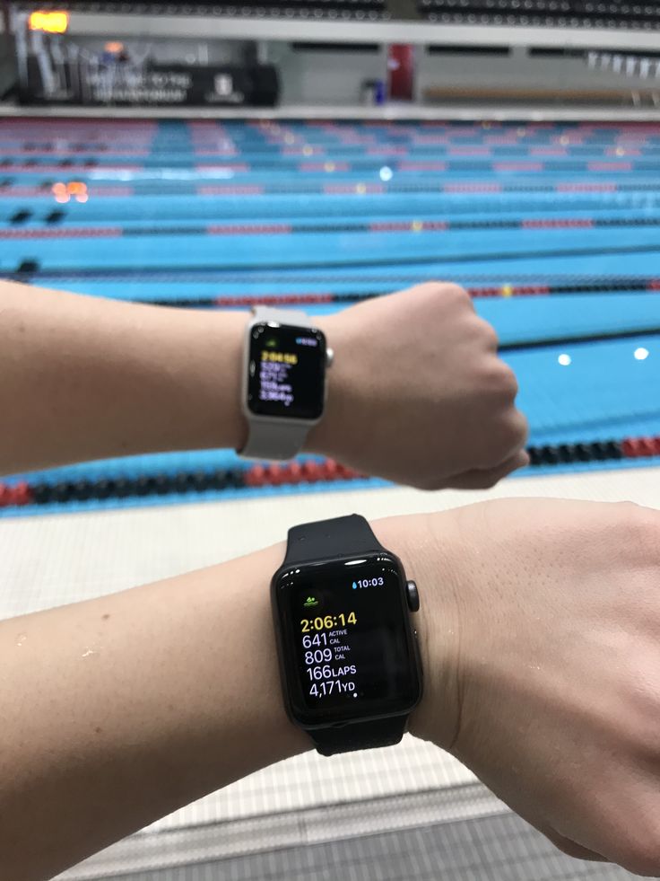 two people wearing smart watches near an indoor swimming pool