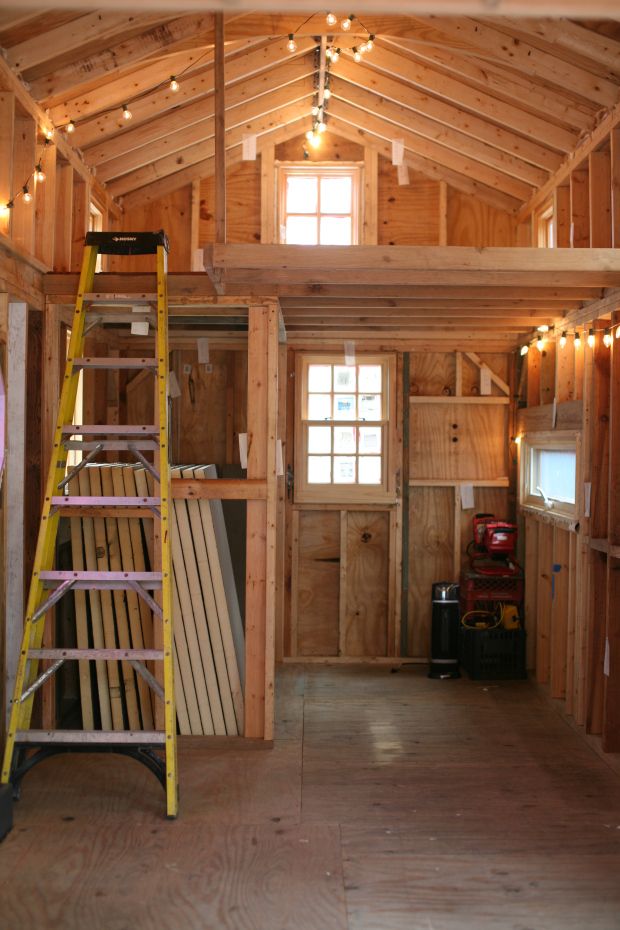 the inside of a wooden building with ladders and lights