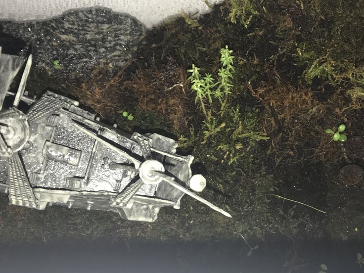 an old model star wars vehicle laying on the ground next to some rocks and grass