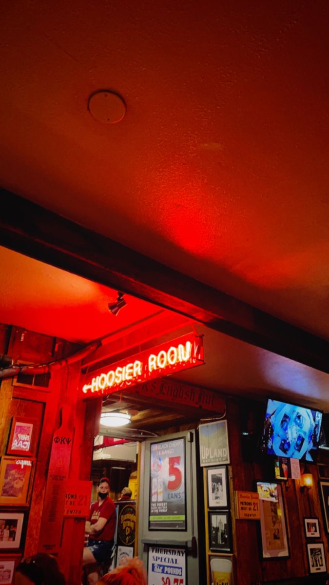 a red neon sign that reads chooser room in front of a bar with people sitting at tables