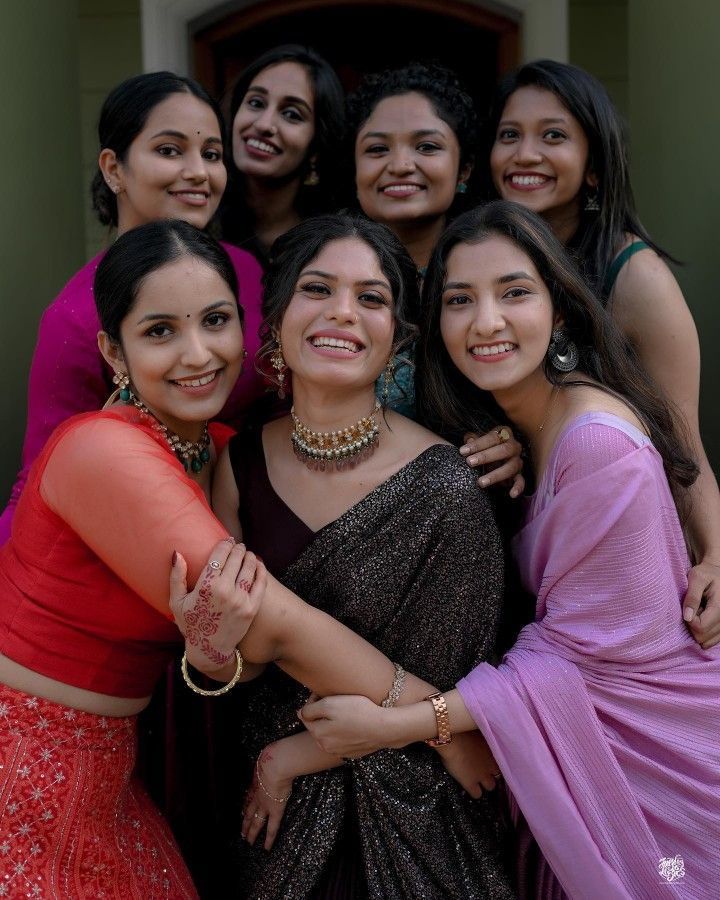 a group of women standing next to each other in front of a door with their arms around one another