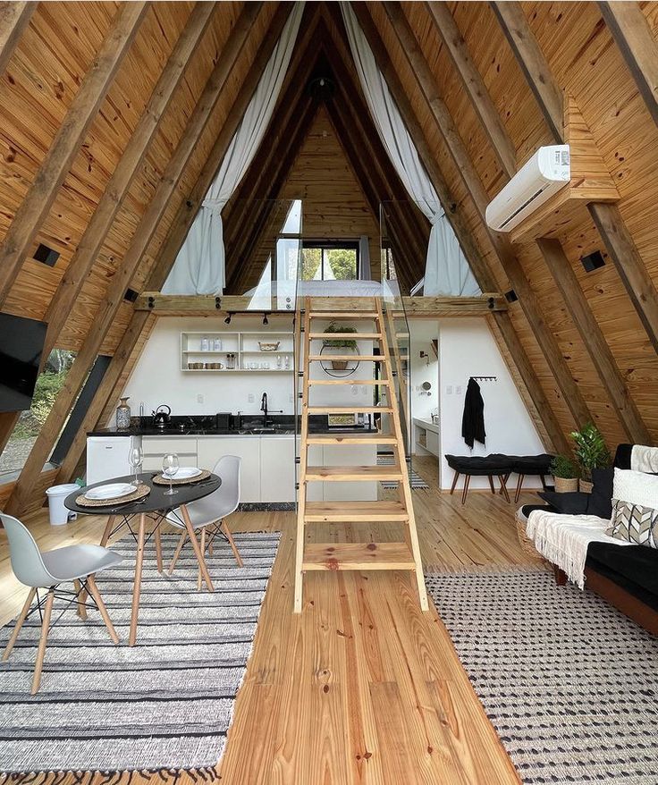 a loft with wood floors and white walls has a ladder leading up to the loft