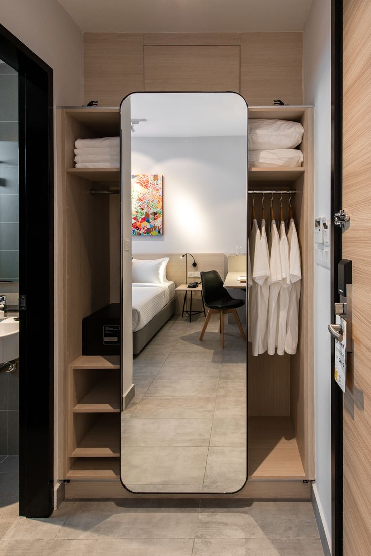 an open closet with clothes hanging on the wall and a mirror in front of it