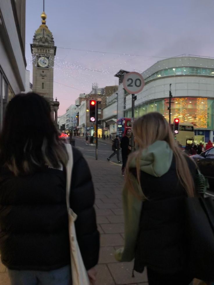 two women walking down the street in front of a clock tower