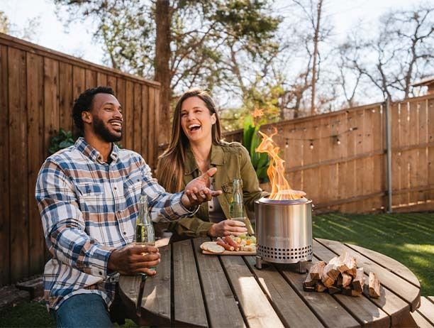 a man and woman sitting at a table with food in front of them, laughing