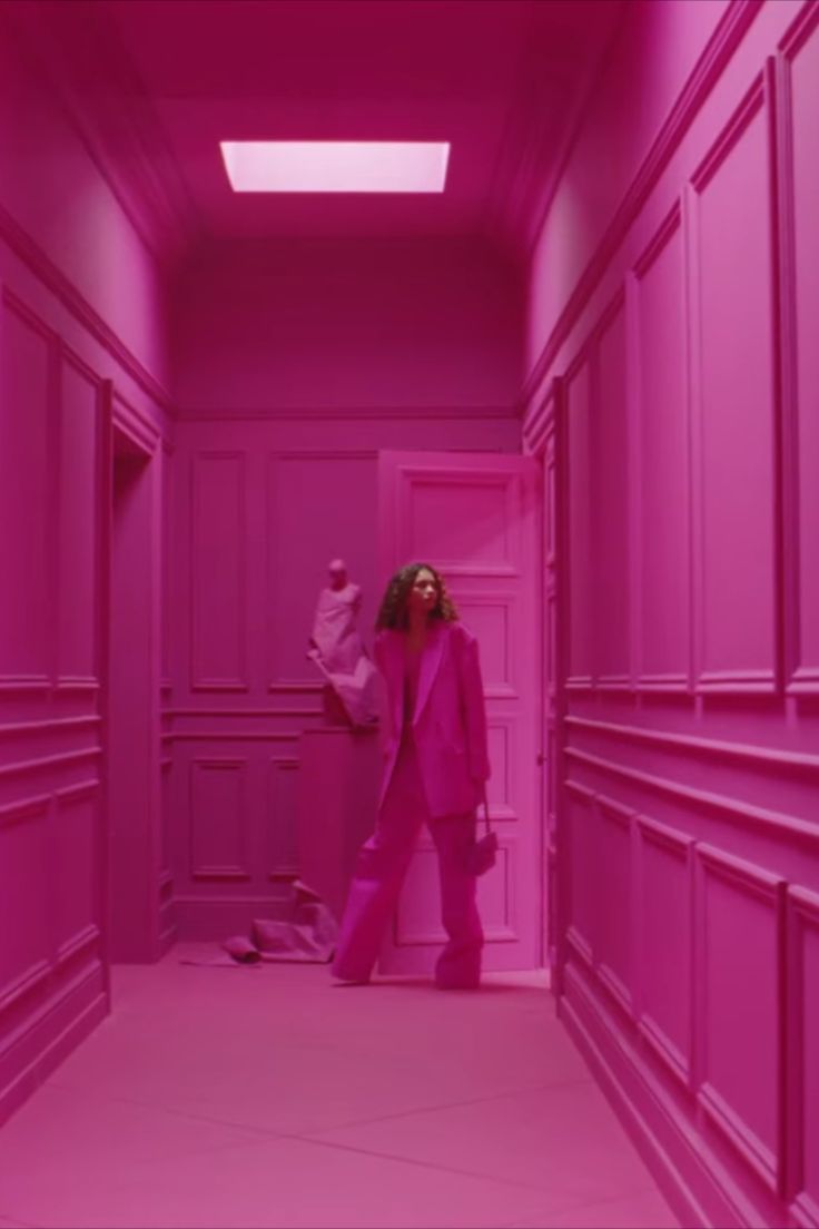 a woman standing in a pink hallway