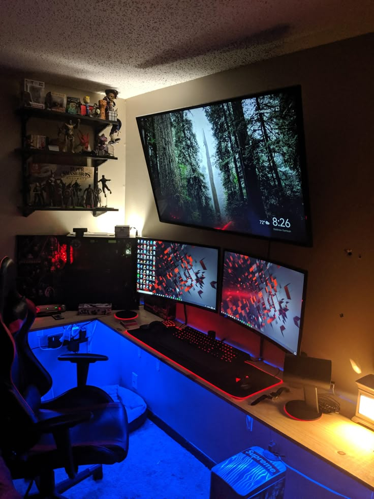 three computer monitors sitting on top of a desk in front of a wall mounted screen