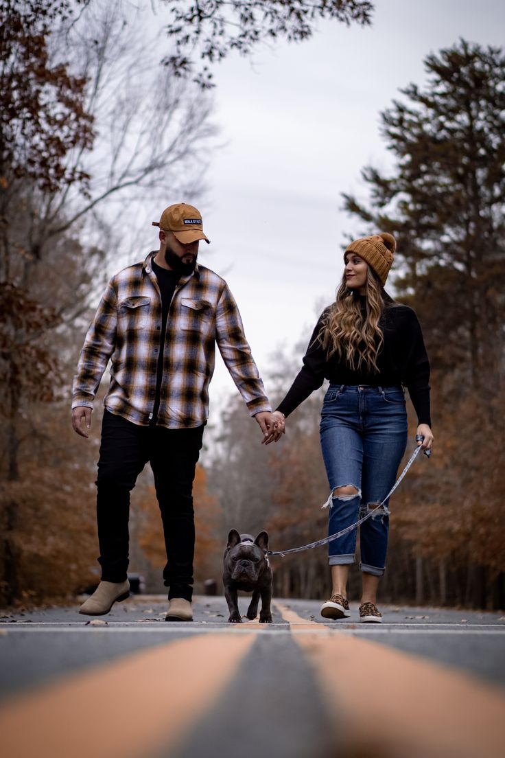 a man and woman holding hands while walking their dog