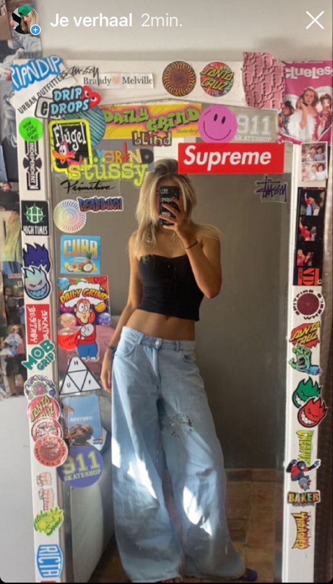 a woman taking a selfie in front of a mirror with stickers all over it