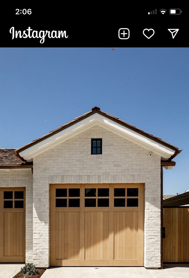 a white brick house with two brown garage doors