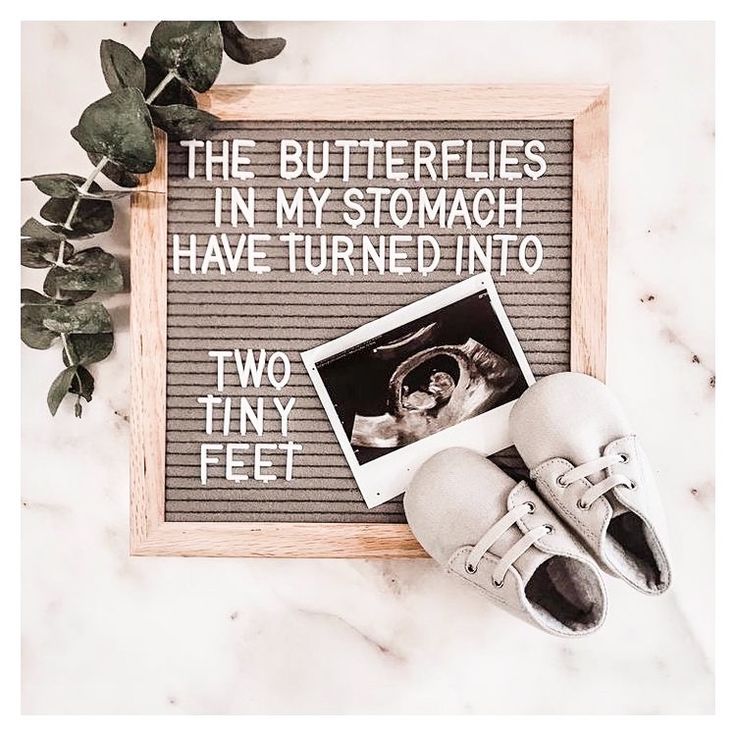 a pair of shoes sitting on top of a table next to a framed photo with the words, the butterflies in my stomach have turned into two tiny feet