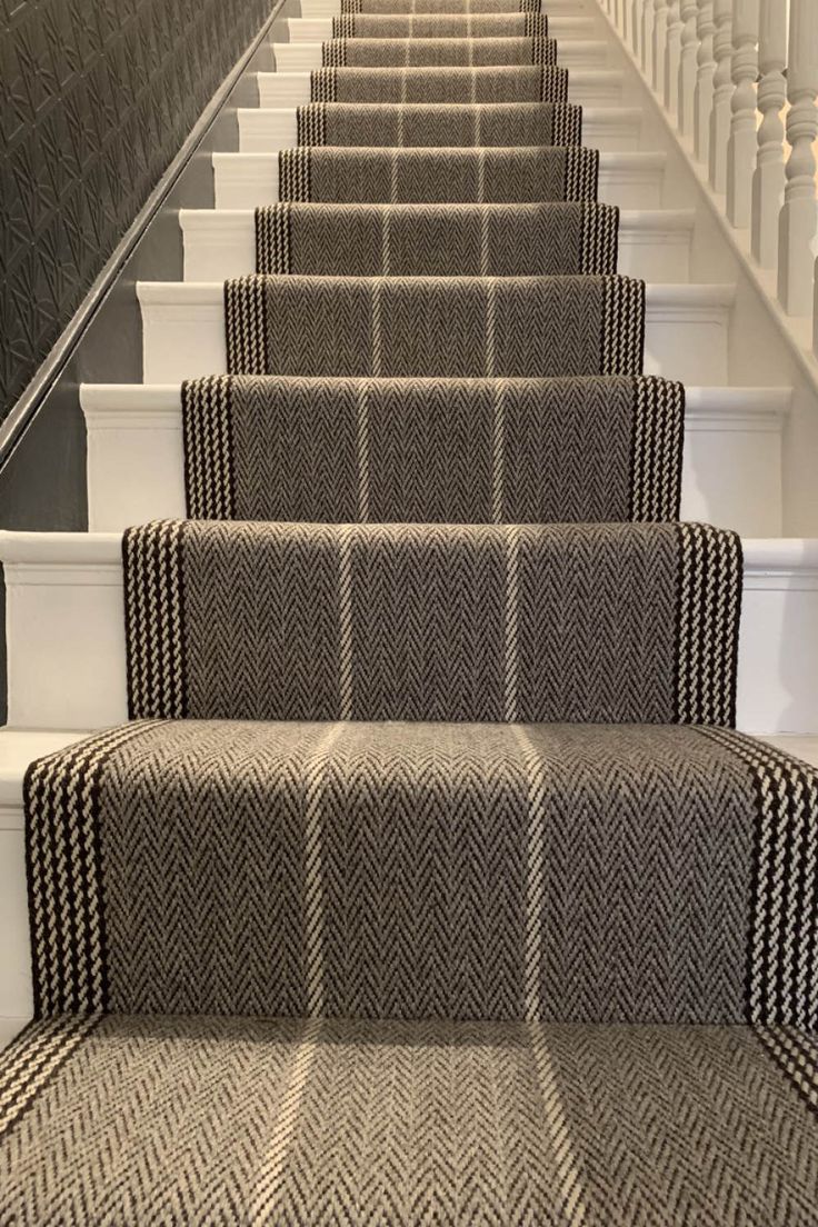 the carpeted stairs are lined with black and white rugs