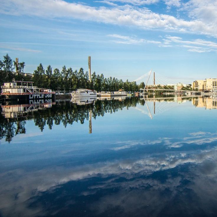 a body of water with boats in it and buildings on the other side, under a partly cloudy blue sky