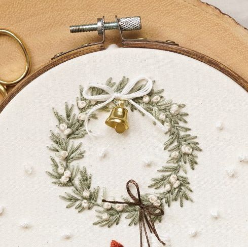 a close up of a cross stitch on a piece of wood with scissors and thread