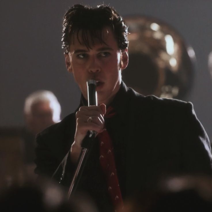 a man holding a microphone up to his mouth while standing in front of an audience